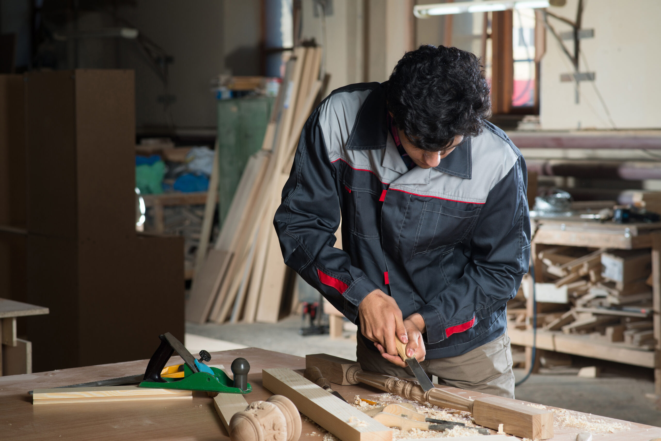 Young craftsman in uniform working at carpentry